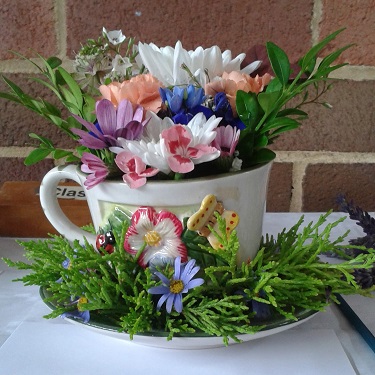 A flower arrangement in a tea cup and saucer