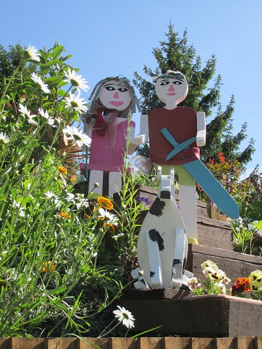 Painted wooden models of a man with a sword, a woman and white dog with white spots